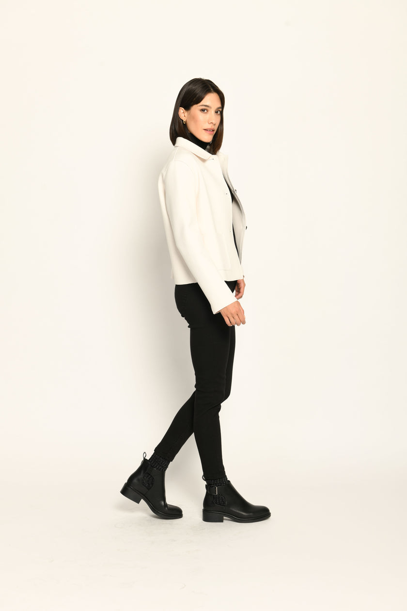 Model trägt weiße Kastenjacke für Damen aus Scuba mit schwarzen großen Knöpfen und aufgesetzten Taschen – Seite rechts