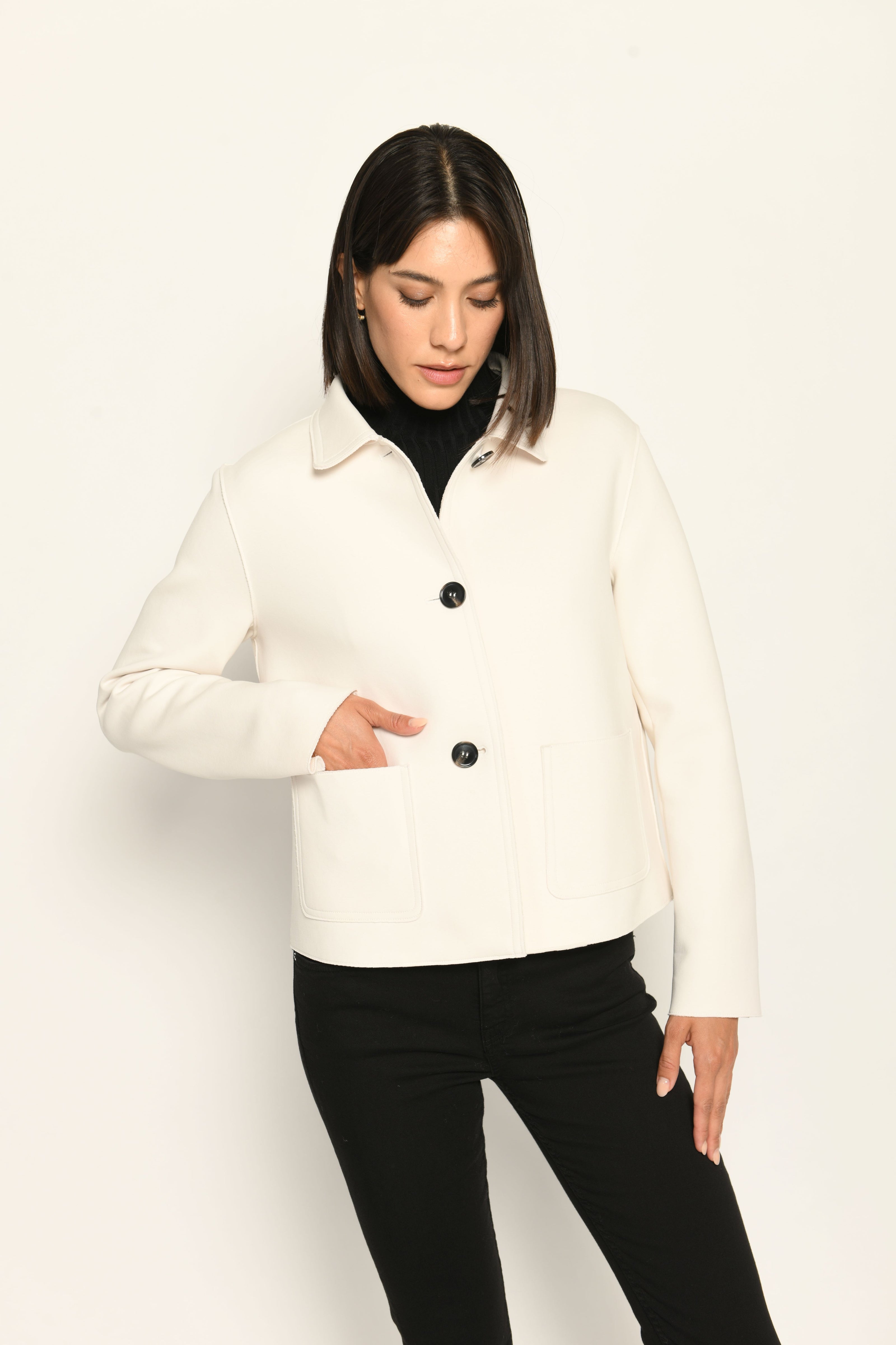 Model trägt weiße Kastenjacke für Damen aus Scuba mit schwarzen großen Knöpfen und aufgesetzten Taschen – Vorderansicht