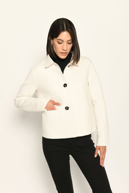 Model trägt weiße Kastenjacke für Damen aus Scuba mit schwarzen großen Knöpfen und aufgesetzten Taschen – Vorderansicht