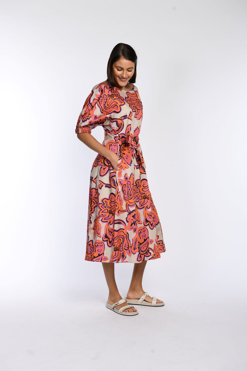 Model trägt Sommerkleid aus 100 % Baumwolle mit floralem Druck in Pink und Orange, Seitenprofil.