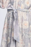 Detailansicht des bedruckten Maxikleids mit zartem Pastellprint, langärmelig, Fokus auf Bindegürtel in der Taille.