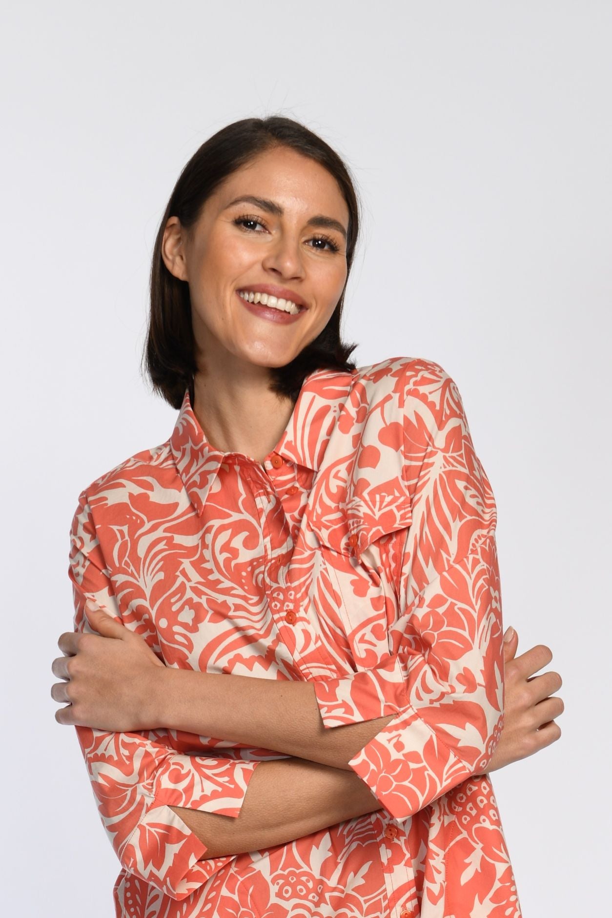 Orange-weiß gemustertes Hemdblusenkleid mit linkseitiger Brusttasche, Ärmelschlitzen und Blusenkragen.