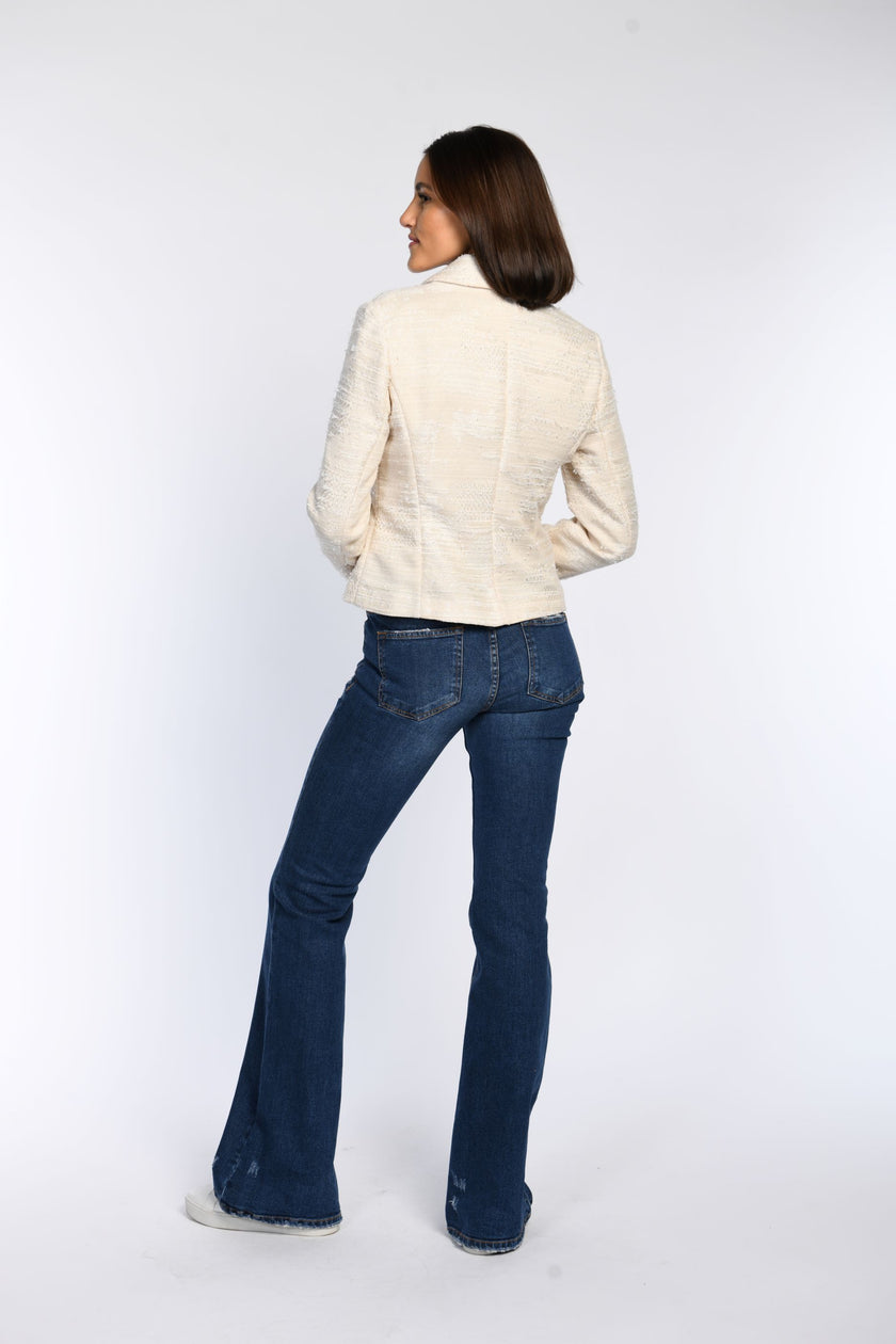 Rückansicht der cremefarbenen Jacquard-Jacke mit sichtbarem Umlegekragen. Kombiniert zur blauen Jeans.
