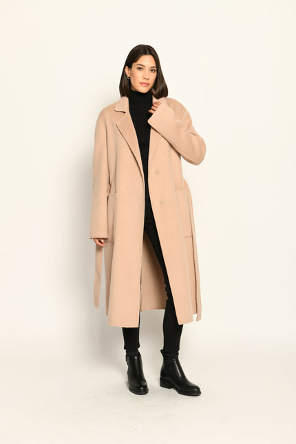 Langer Mantel für Damen in der Farbe Camel mit Reverskragen, Bindegürtel und aufgesetzten Taschen – offen getragen.