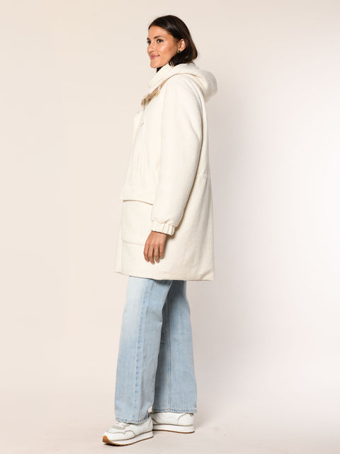 Model trägt einen geraden geschnittenen Wollmantel mit Kapuze in der Farbe offwhite - Seitenansicht.