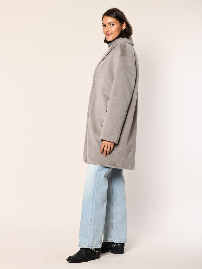 Model trägt einen leger geschnittenen Webpelz Manel mit Reverskragen in der Farbe taupe - Seitenansicht.