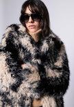 Damenmantel aus langhaarigem schwarz-beigen Webpelz für den Winter – Vorderansicht, geschlossen getragen