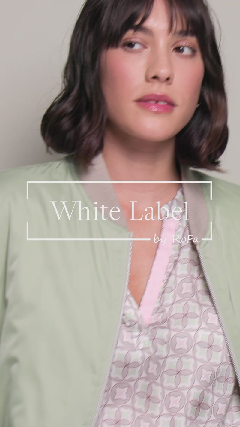 Model präsentiert im Video eine bedruckte, locker geschnittene Tunikabluse mit langen Ärmeln.