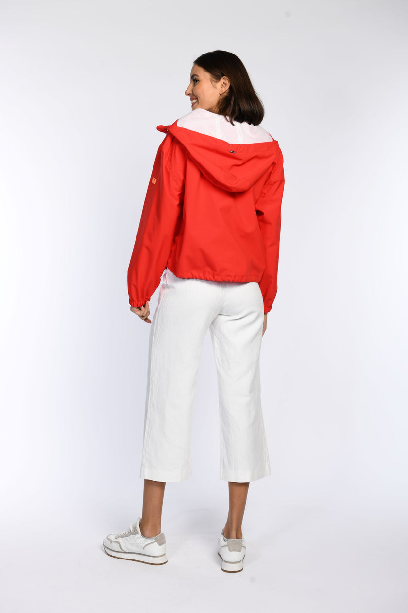 Rückansicht der roten Regenjacke am Model - Fokus auf die Kapuze und den Tunnelzug am unteren Saum.