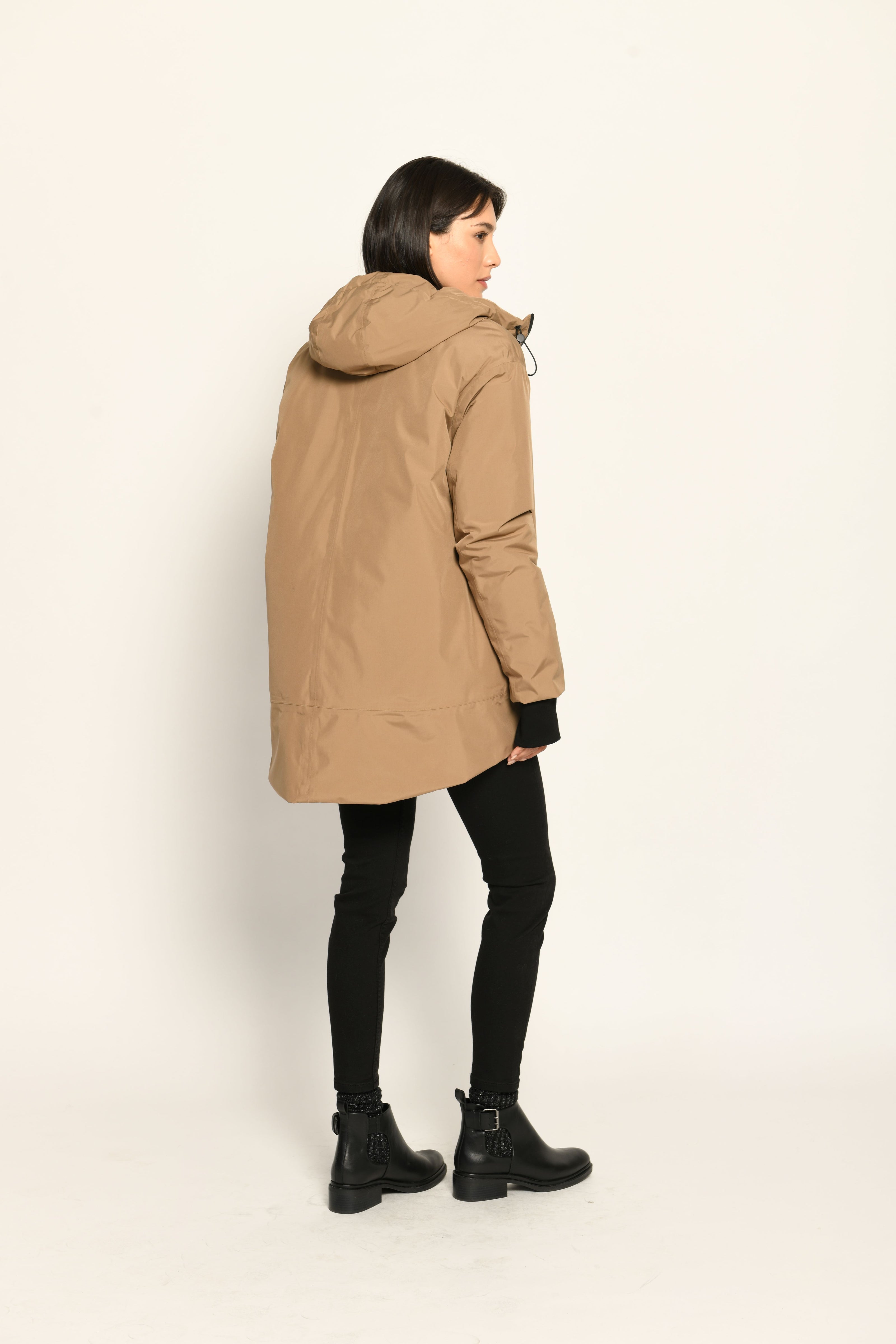 Model trägt Regenmantel für Damen in der Farbe Camel, lässig kombiniert zu schwarzer Jeanshose – Rückansicht