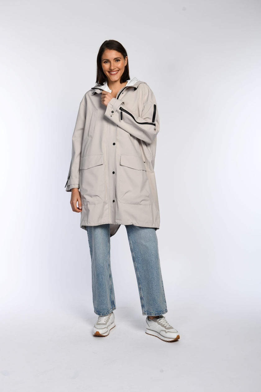 Model trägt einen knielangen Regenparka in hellem Beige. 