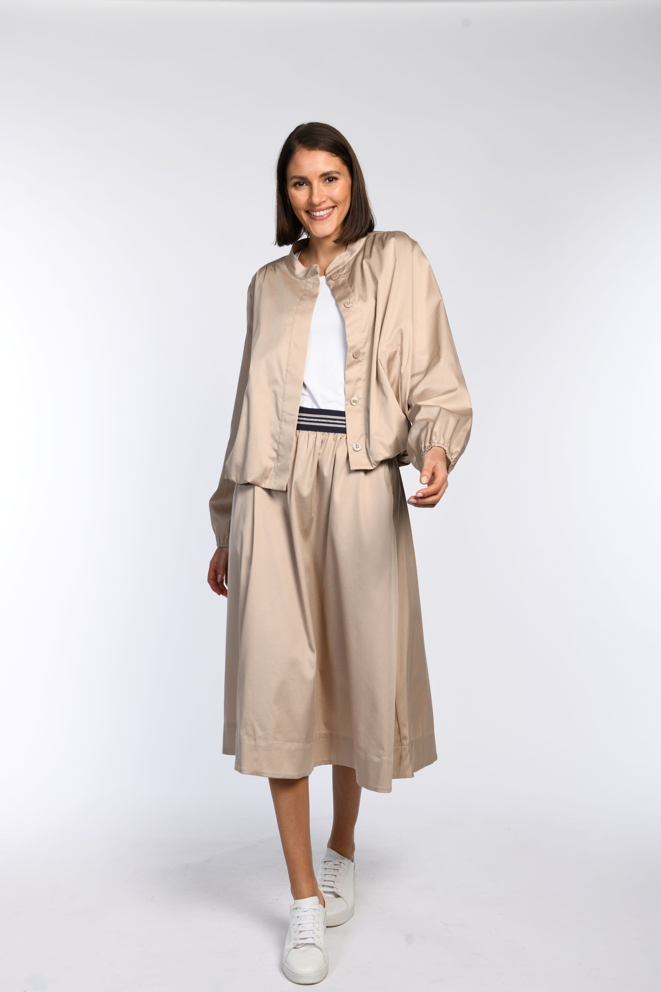 Model trägt einen beigefarbenen Rock mit passendem, locker geschnittenem Blouson – Vorderansicht.