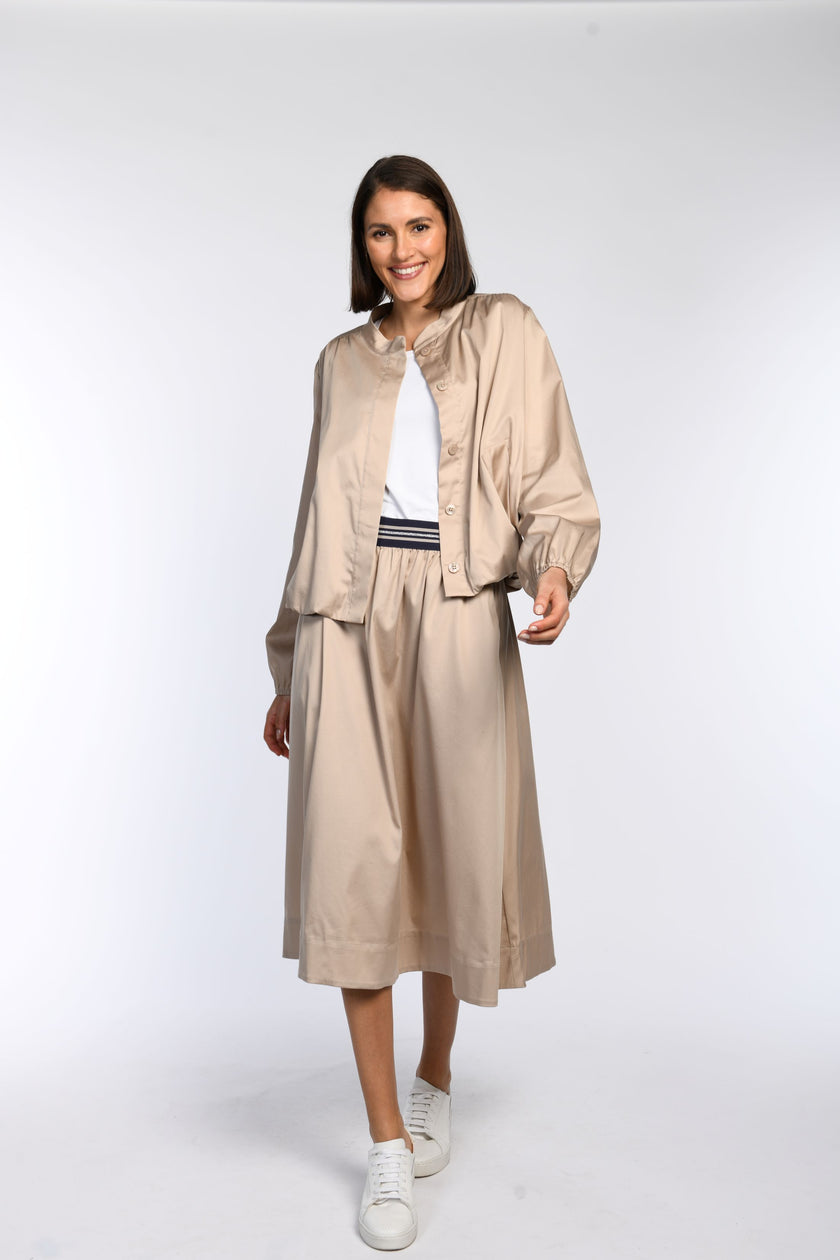 Model trägt einen beigefarbenen Rock mit passendem, locker geschnittenem Blouson – Vorderansicht.