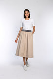 Model trägt beigen Rock in A-Linie mit gestreiftem Gummibund und schrägen Eingriffstaschen.