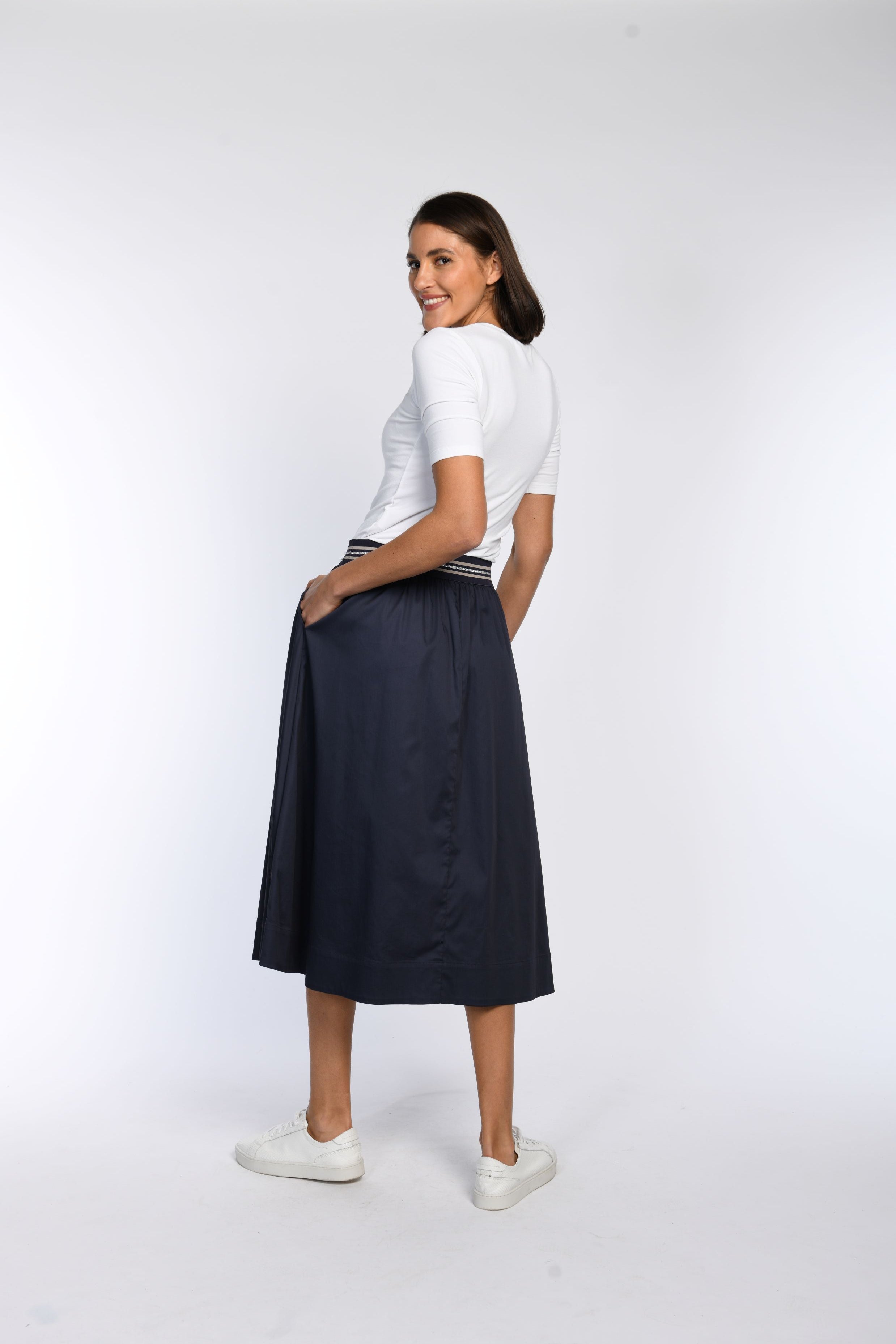 Model trägt blauen Rock mit seitlichen Eingriffstaschen – Rückenansicht.