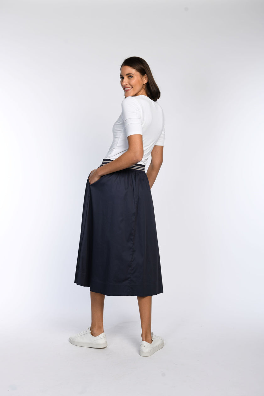 Model trägt blauen Rock mit seitlichen Eingriffstaschen – Rückenansicht.