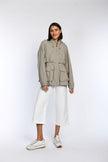 Model trägt eine geschlossene, sommerliche Jacke in Taupe mit zwei Seitentaschen und elastischen Bündchen an den Ärmeln.