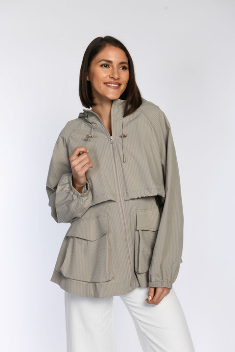 Model in einer sommerlichen, taupefarbenen Jacke mit zwei Seitentaschen und elastischen Ärmelbündchen.