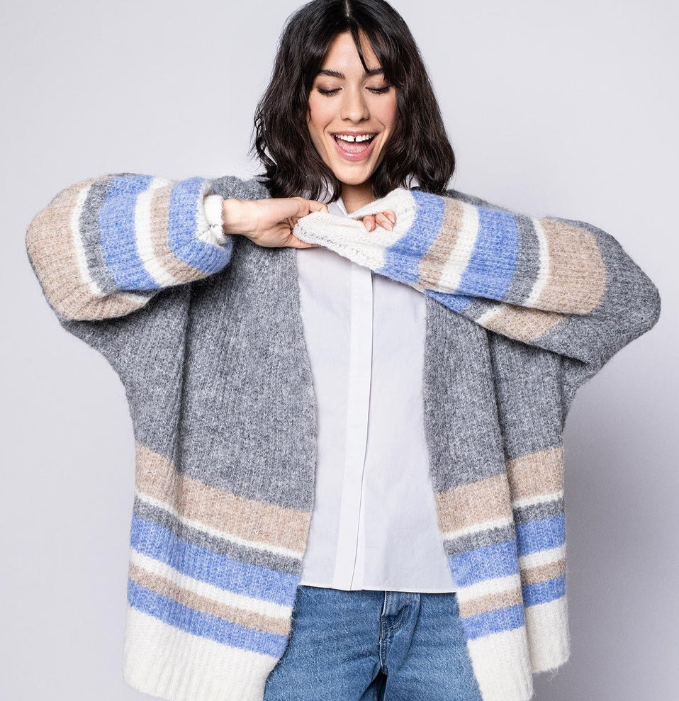 Offene graue Strickjacke für Damen mit beigen, blauen und cremefarbenen Querstreifen, kombiniert mit weißer Bluse. - Shop the Look