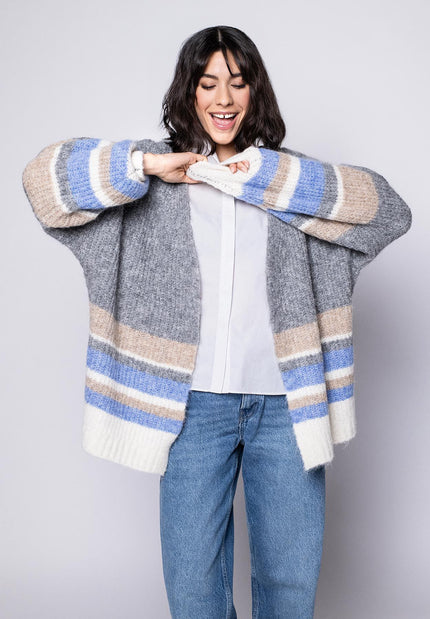 Offene graue Strickjacke für Damen mit beigen, blauen und cremefarbenen Querstreifen, kombiniert mit weißer Bluse.
