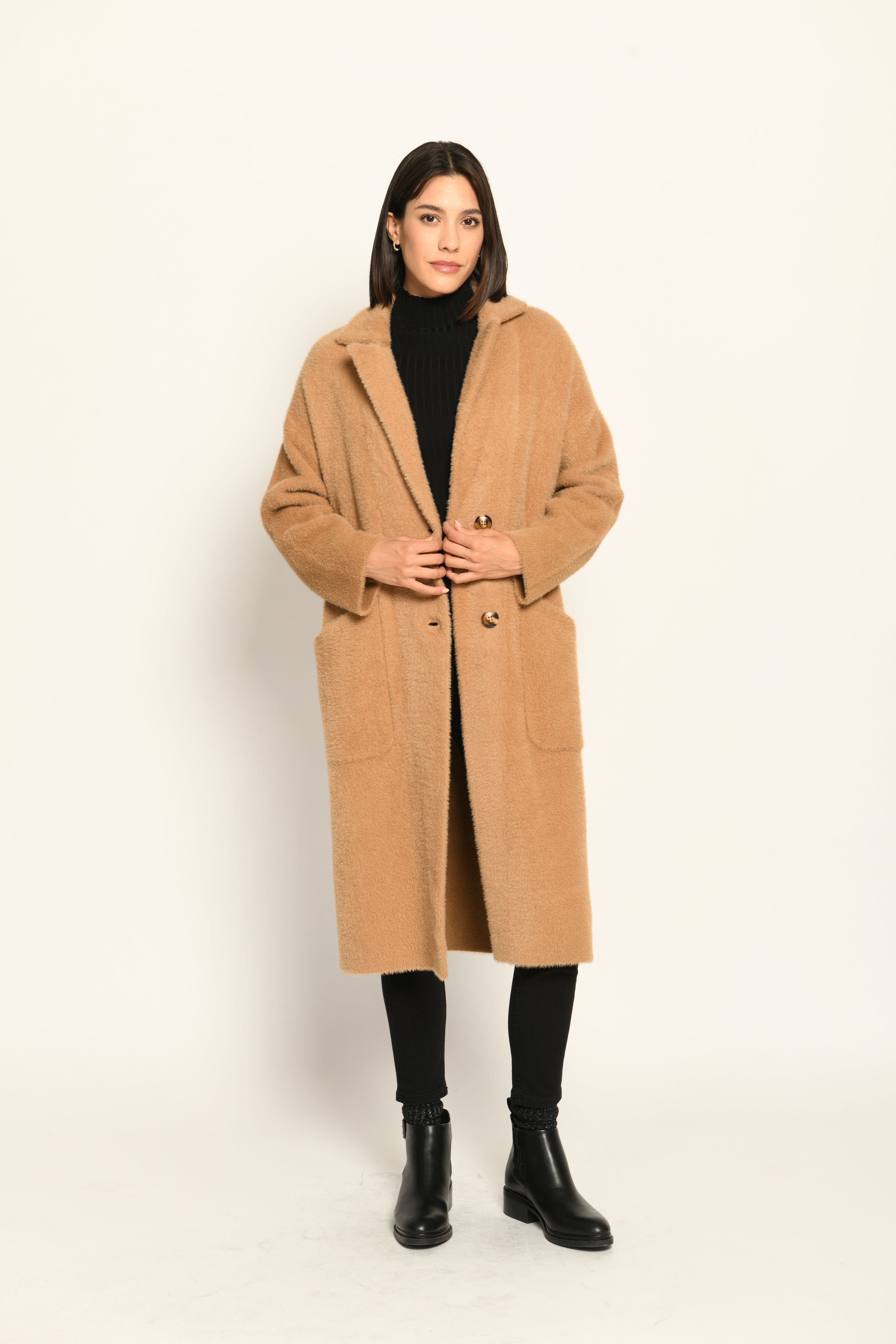 Model trägt knielangen braunen Strickmantel für Damen lässig kombiniert zu schwarzer Jeans – Vorderseite