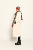 Model trägt Strickmütze, Schal und Stulpen im Leo-Dessin, lässig kombiniert zu einem cremefarbenen Mantel – Seitenansicht