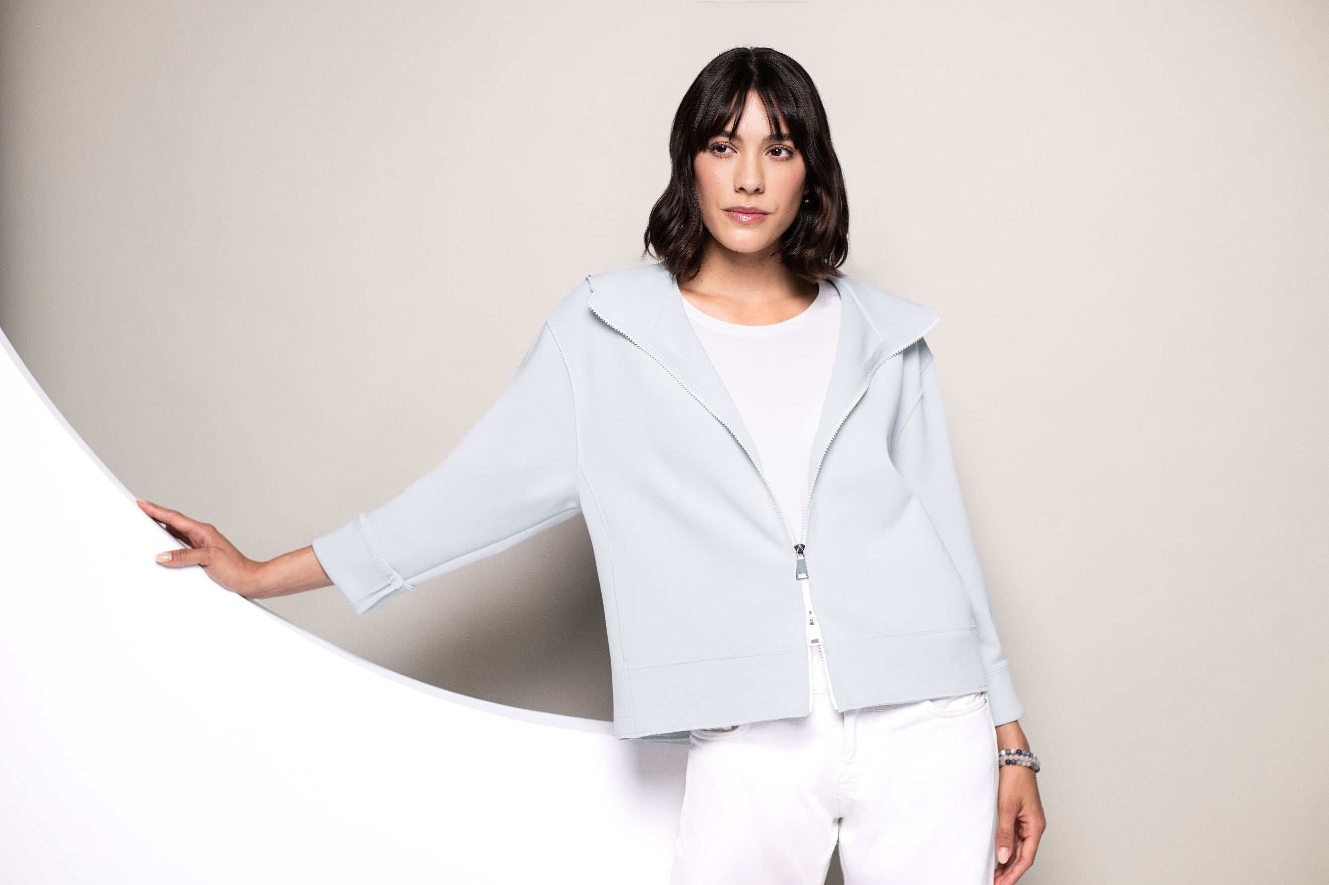 Model in blauer Sweatjacke, durch Zwei-Wege-Zipper nur im mittleren Teil fixiert.