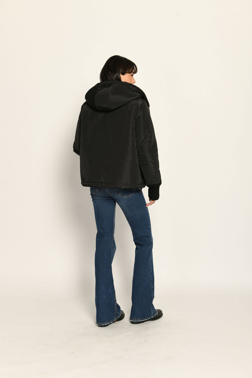 Model trägt schwarze gefütterte Wendejacke aus wärmendem Teddy-Webpelz mit Kapuze – Nylon-Rückansicht