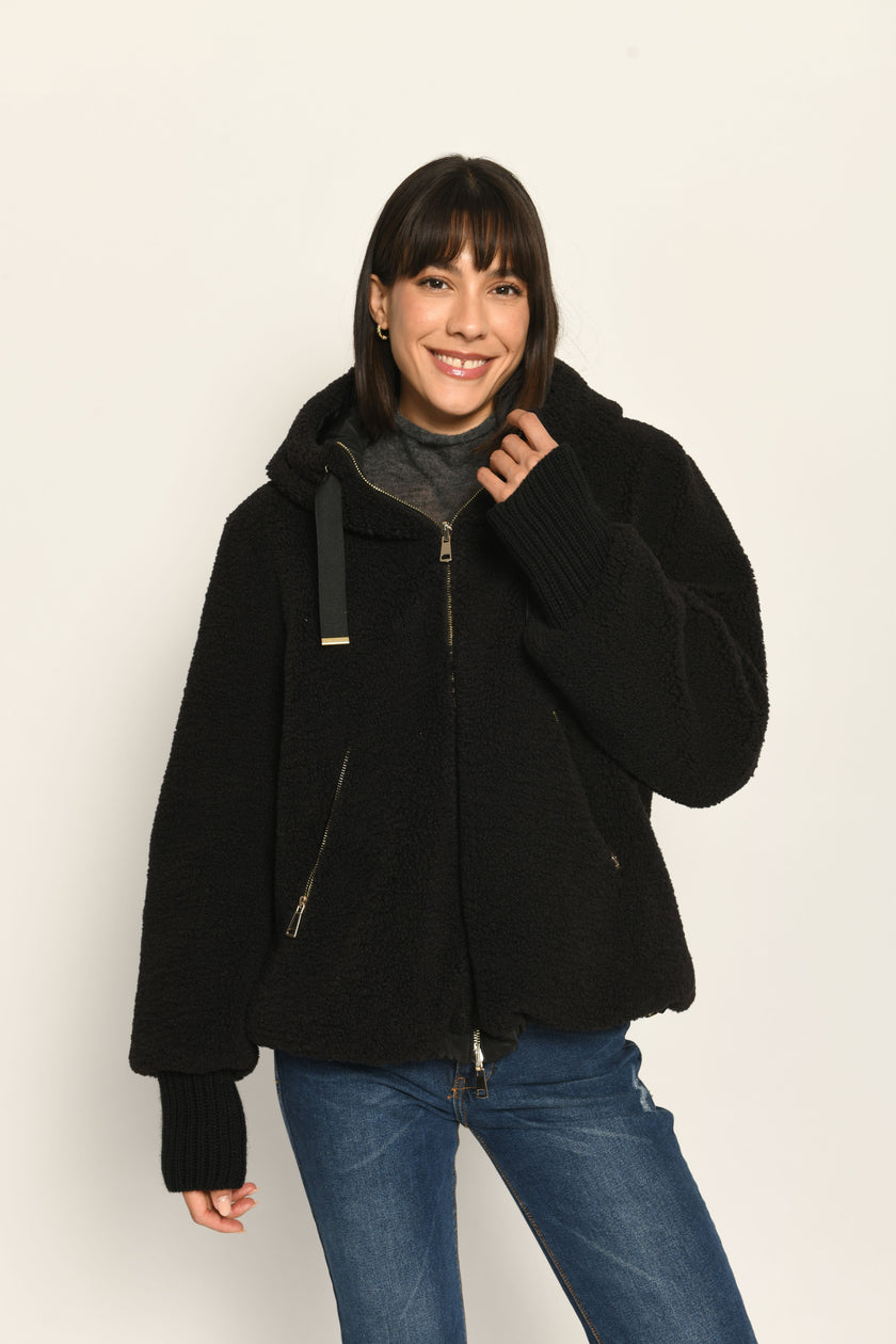 Model trägt schwarze gefütterte Wendejacke aus wärmendem Teddy-Webpelz mit Kapuze – Nahaufnahme Teddy-Ansicht