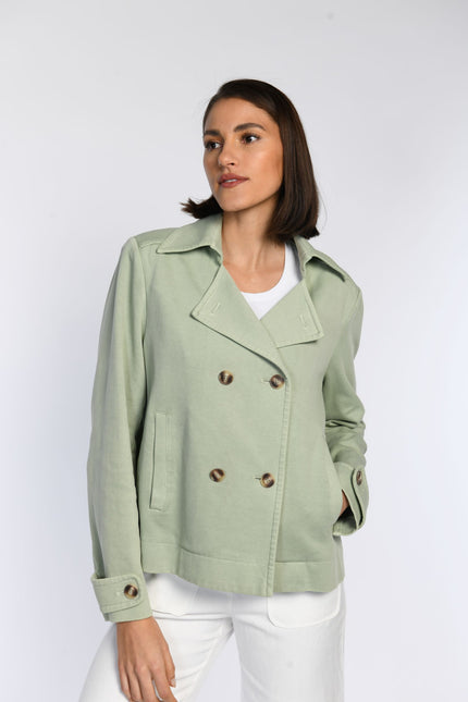 Model trägt geschlossene Trenchjacke aus Jersey mit zweireihigem Knopfverschluss.