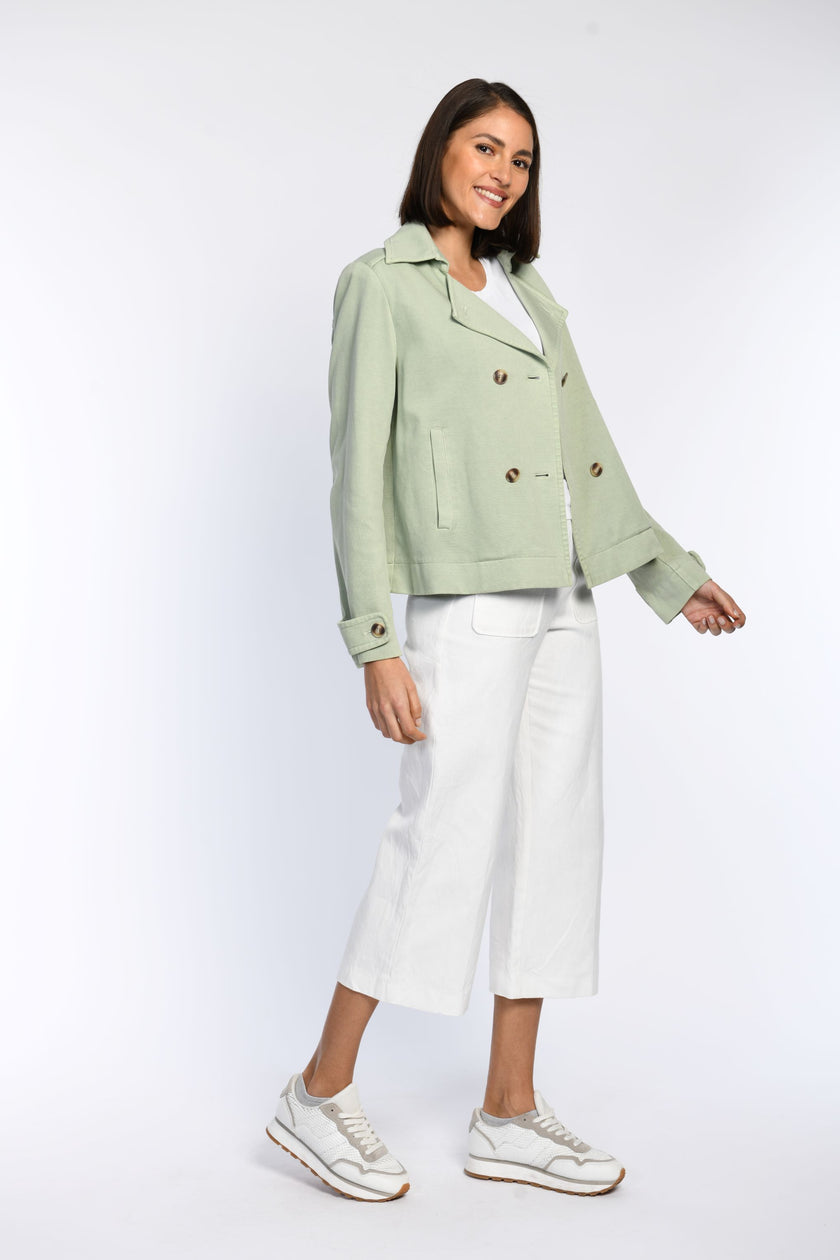 Model trägt Jersey-Trenchjacke in der Farbe Pastellgrün mit Leistentaschen.