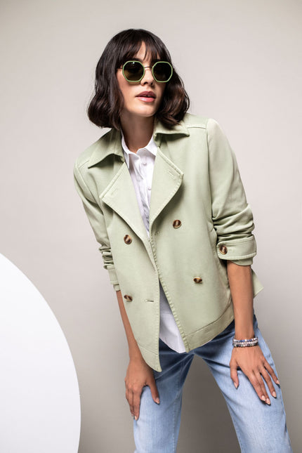 Model in pastellgrüner, zweireihiger Jersey-Trenchjacke mit Umlegekragen.