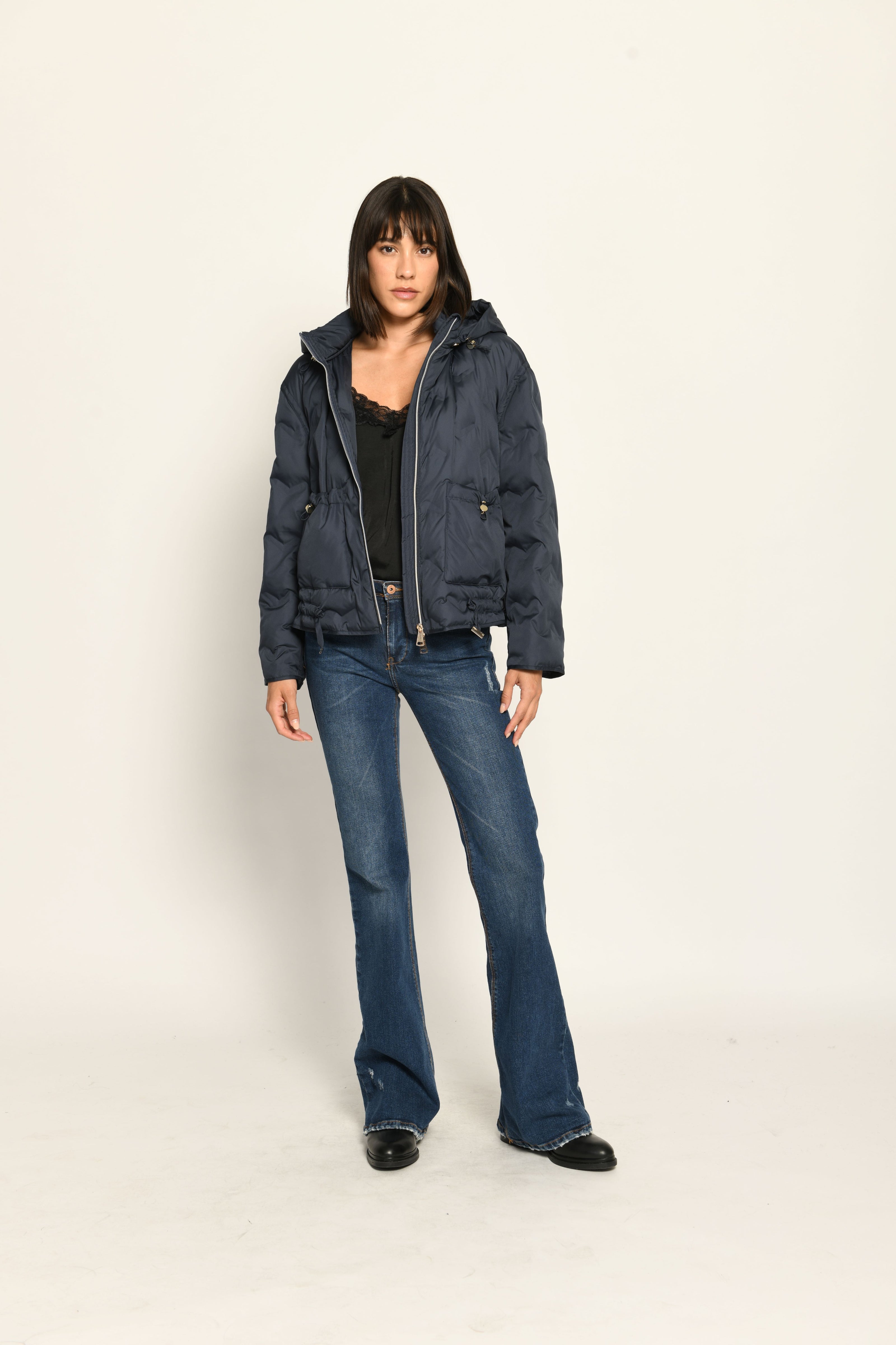 Offen getragene sportive dunkelblaue Steppjacke für Damen mit Kapuze zu dunkelblauer Jeans – Vorderansicht