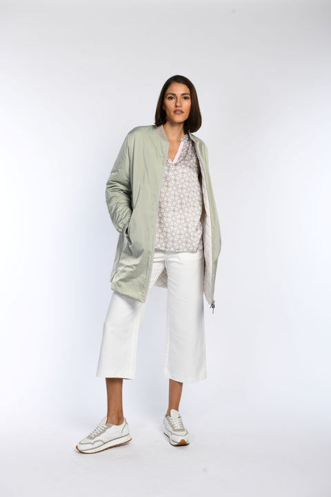 Model trägt unseren Wendeblouson in Mintgrün zur Bluse und weißen Jeans.