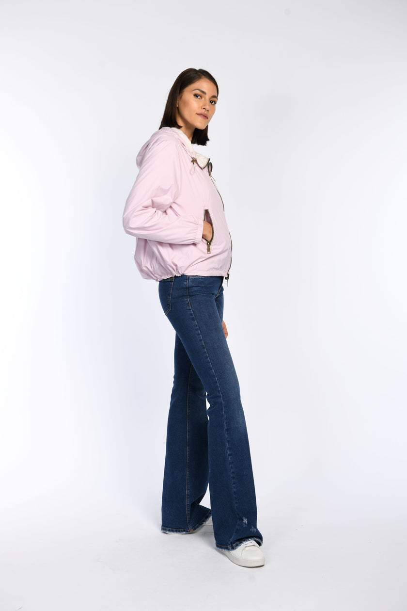 Model trägt in Seitenansicht geschlossene Wendejacke in Rosa mit Reißverschlusstaschen.